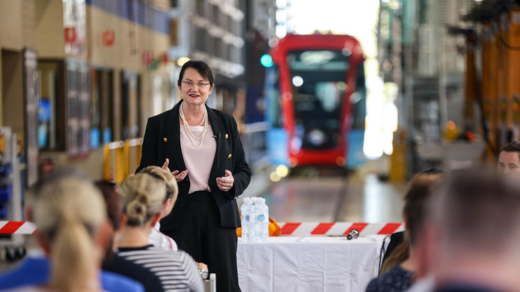 Speaker Catherine Baxter (Chief Operating Officer, Metro Trains Melbourne, addrssing the crowd with a tram in the background