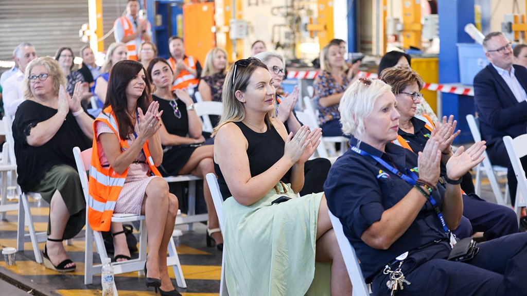 A photo of guests at the event, sitting on chairs, applauding