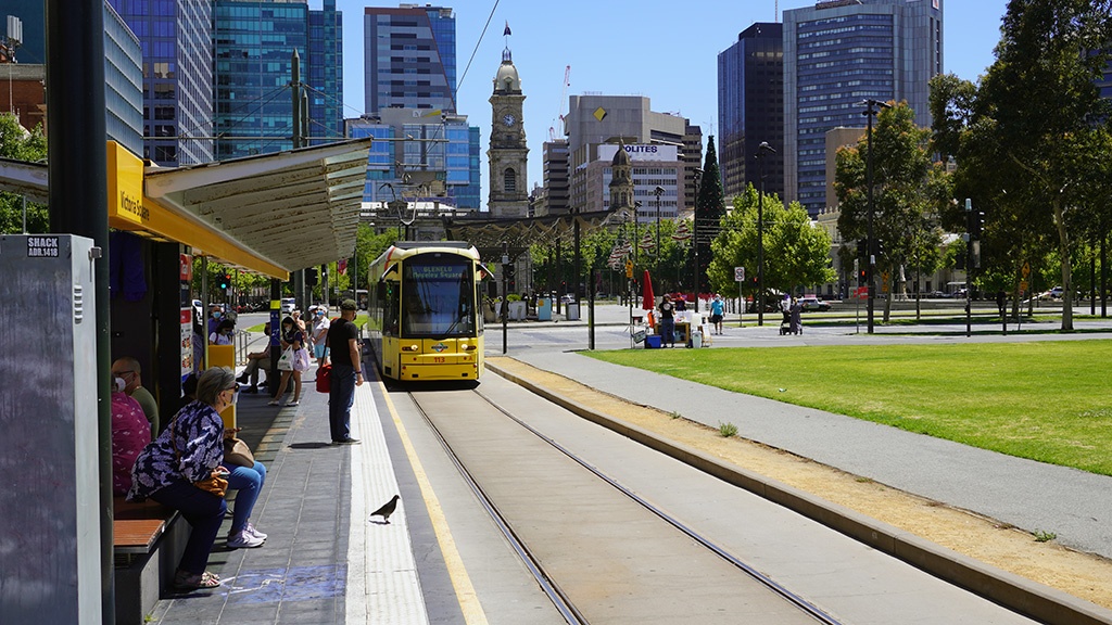 A yellow Flexity trams arriving at the Victoria Square platform where customers are waiting.